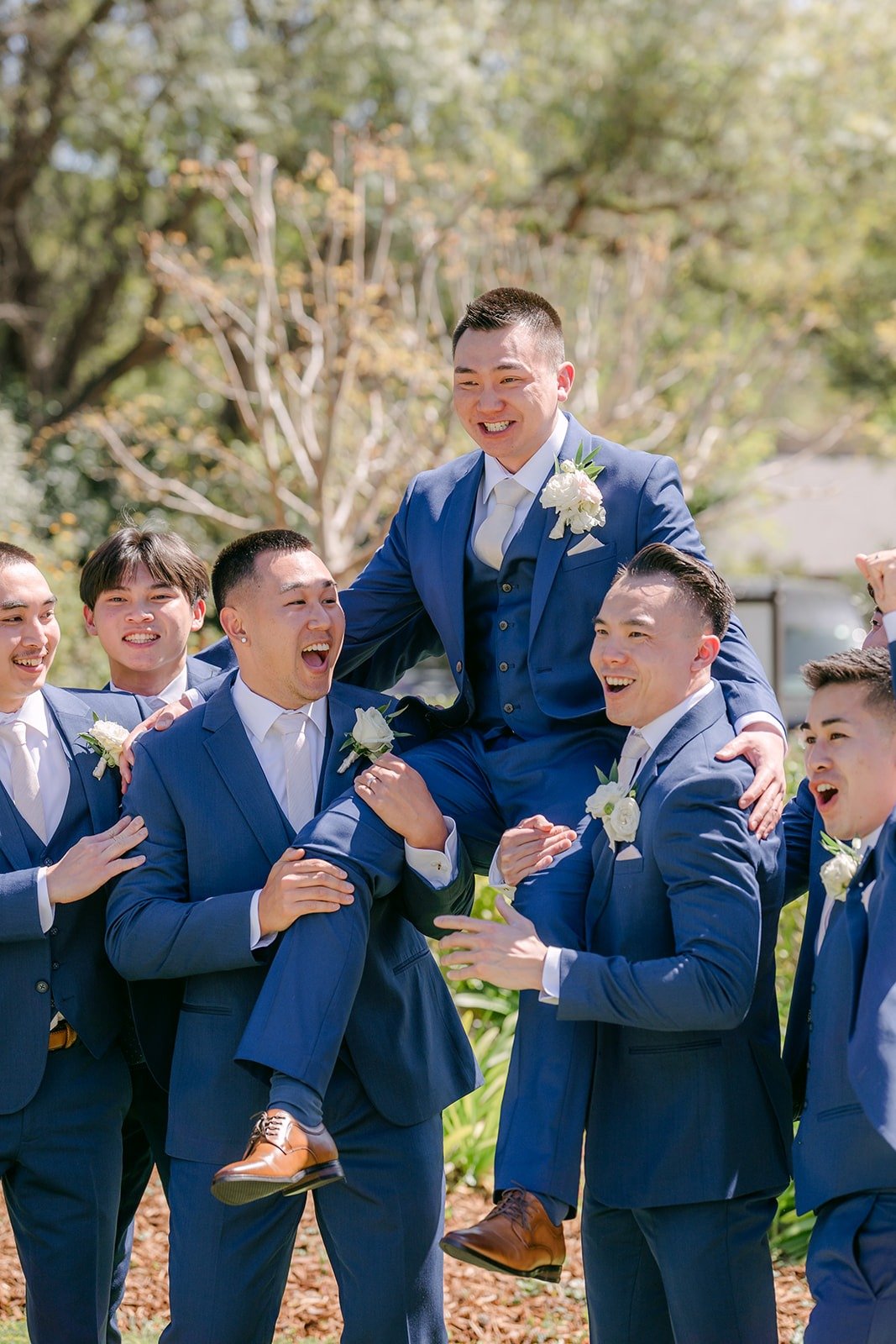 Alex's groomsmen lifting him up in the air and laughing