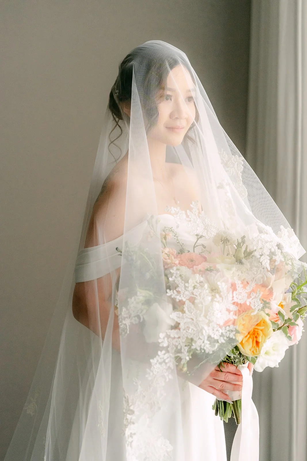 Amanda holding her bouquet under her cathedral veil.