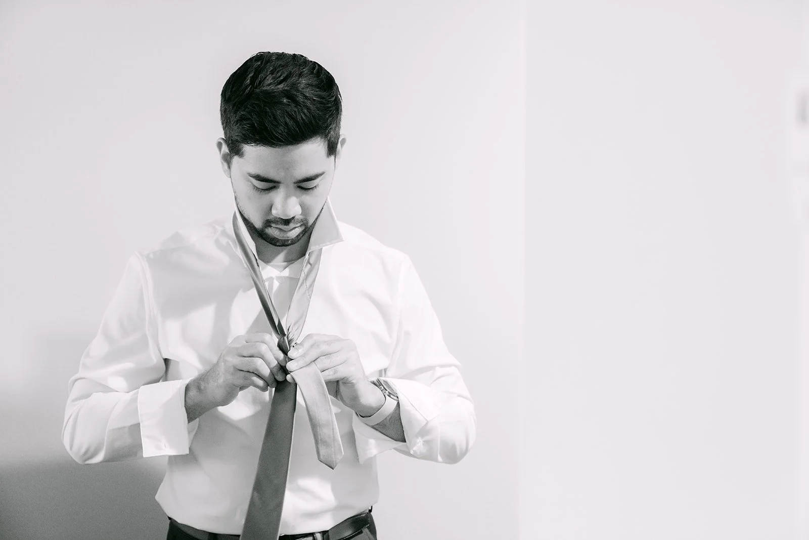 Mark tying his tie in a black and white portrait at the hotel