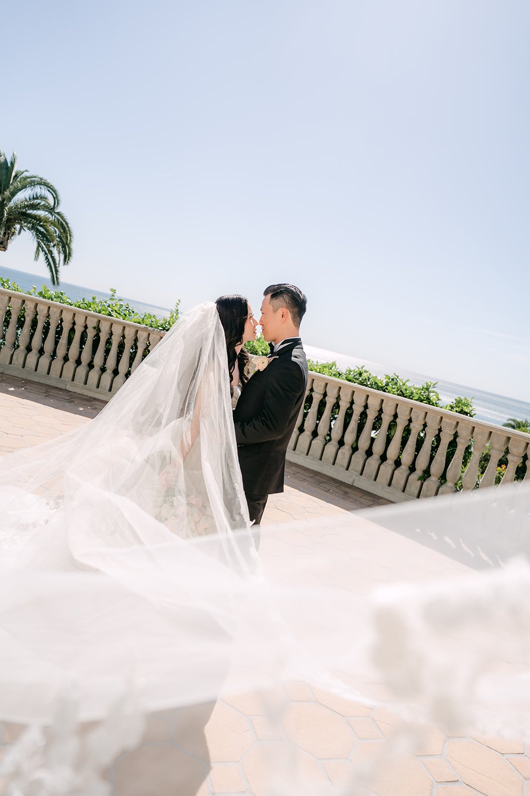 Bride's veil billowing as the couple stands on the terrace