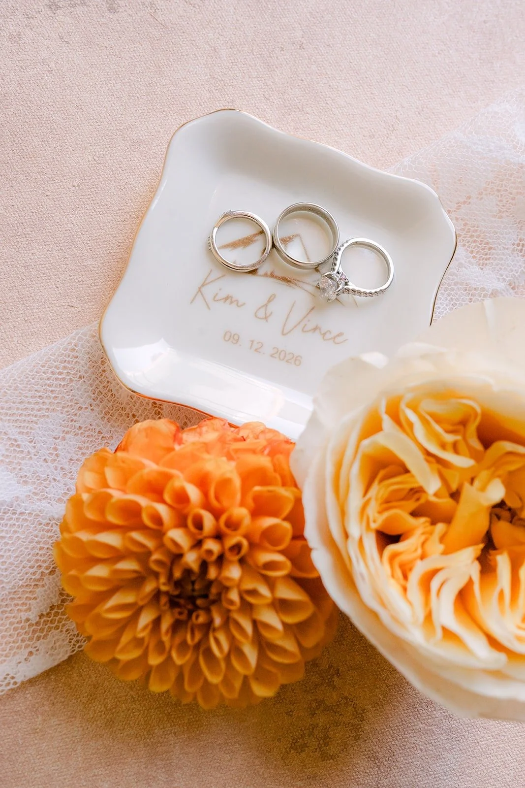 Wedding bands in the ring dish with a peach dahlia and garden rose