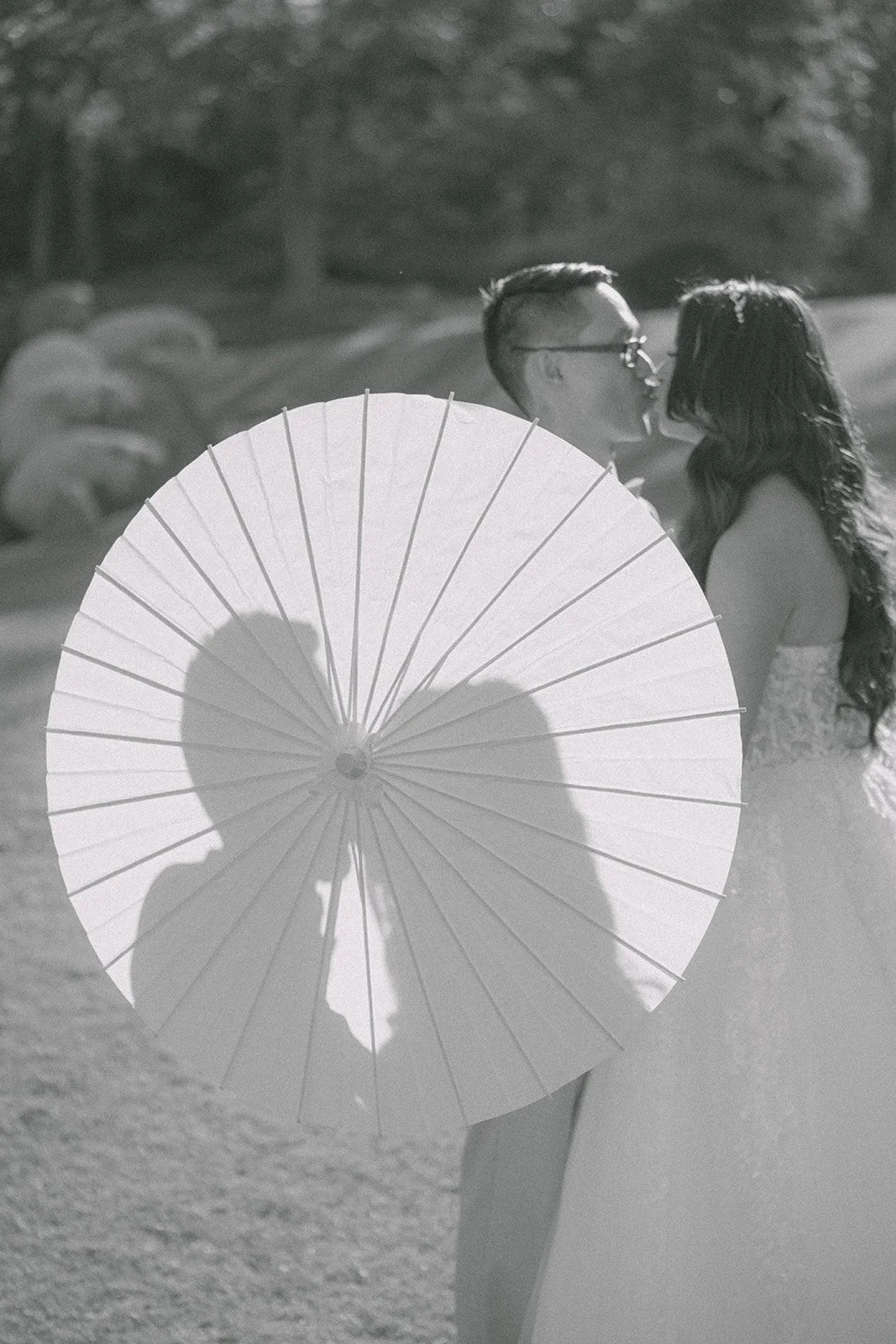 Black and white silhouette of Sandra and Kevin kissing behind a parasol.