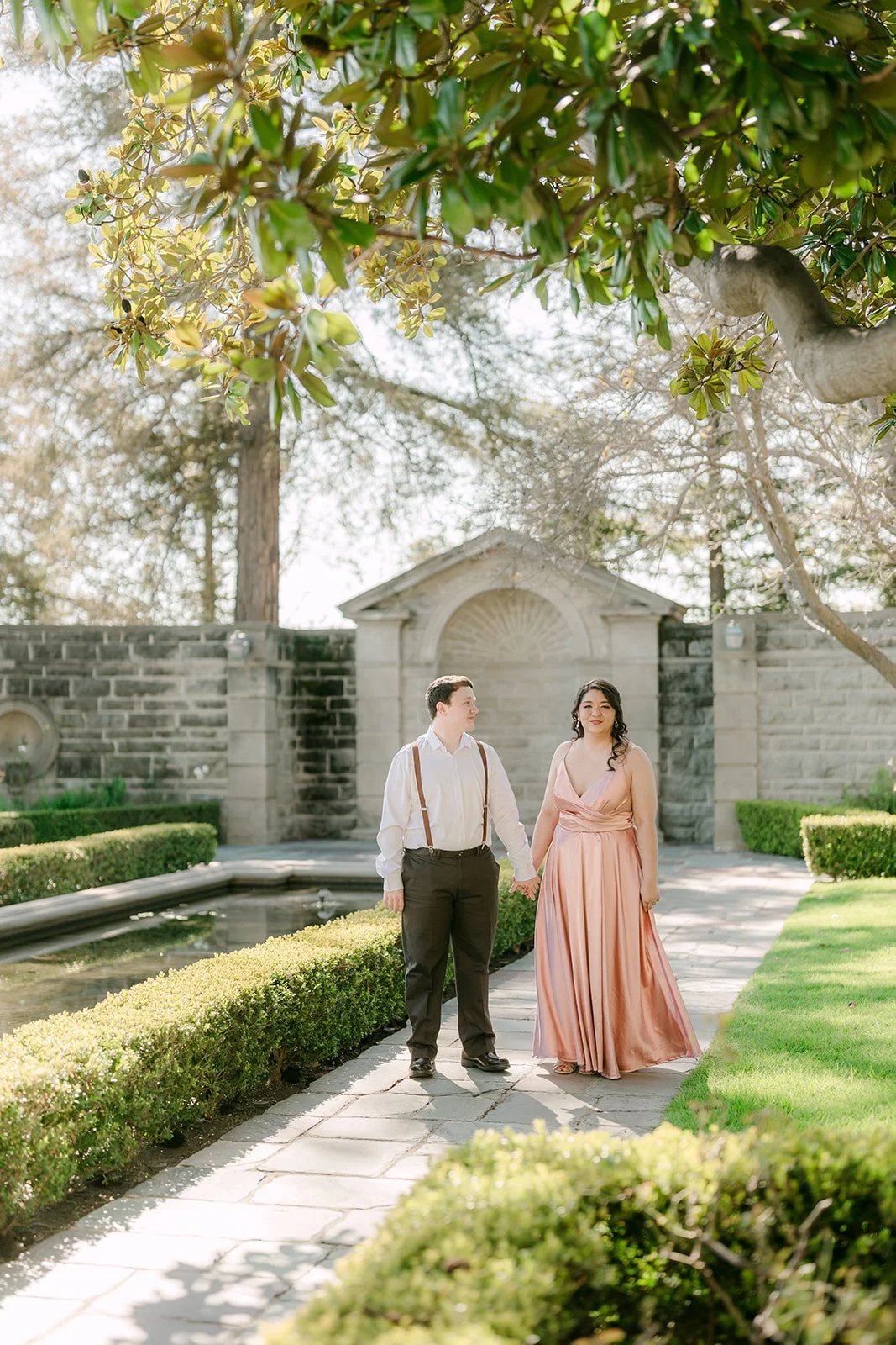 The couple standing beside the reflecting pool in Greystone's formal garden.