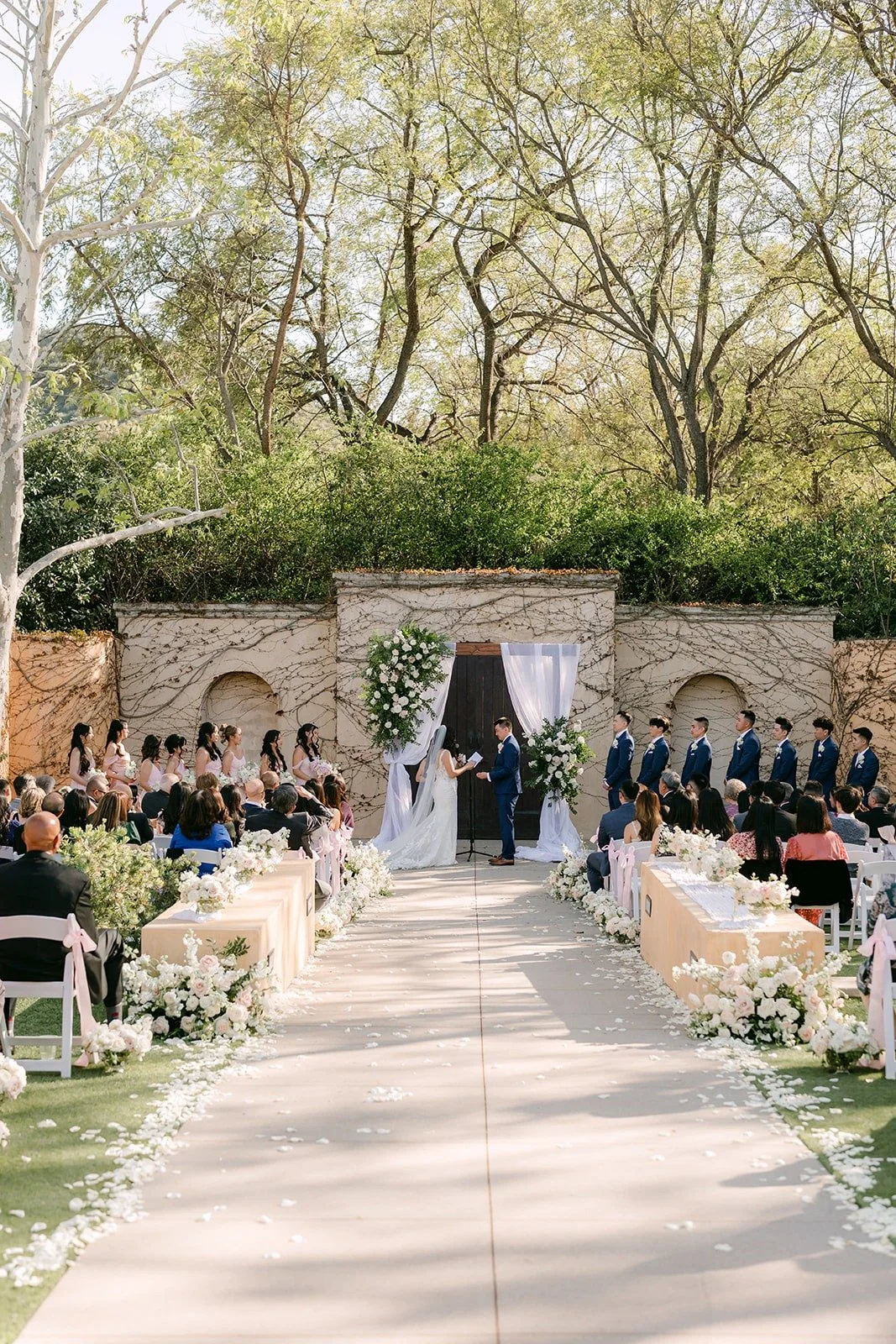 The ceremony aisle leading to the floral arch and stone wall at Los Robles Greens