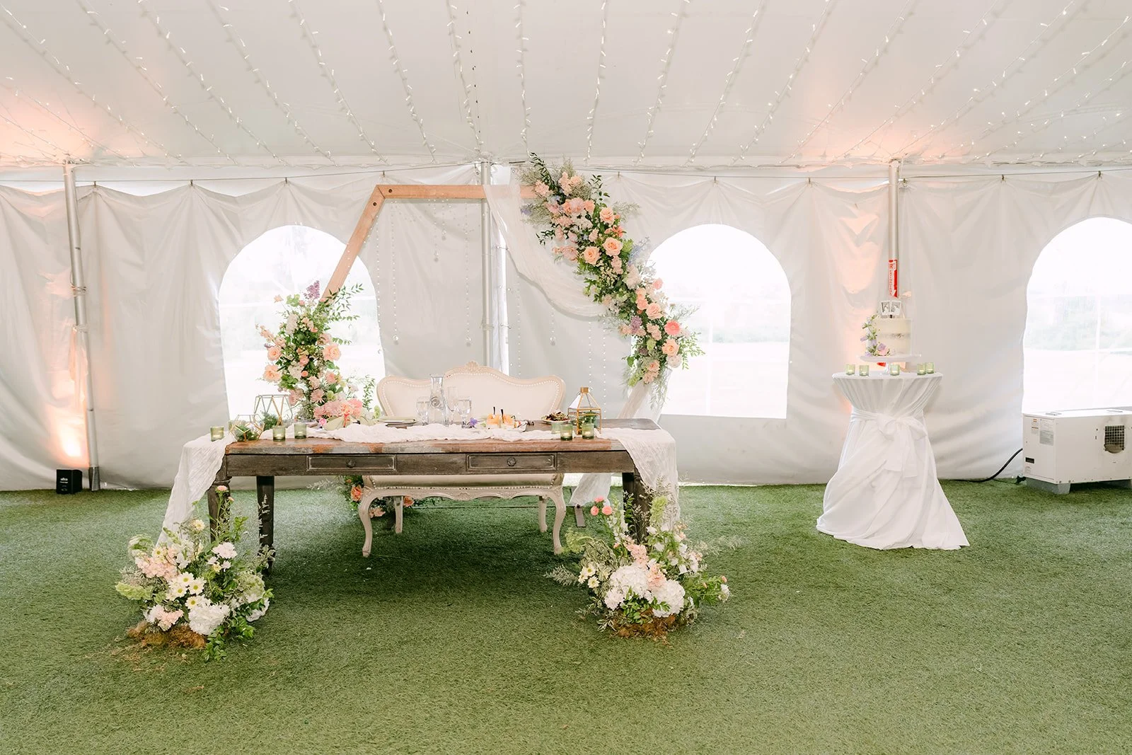 Sweetheart table beneath a hexagon arch with pastel florals