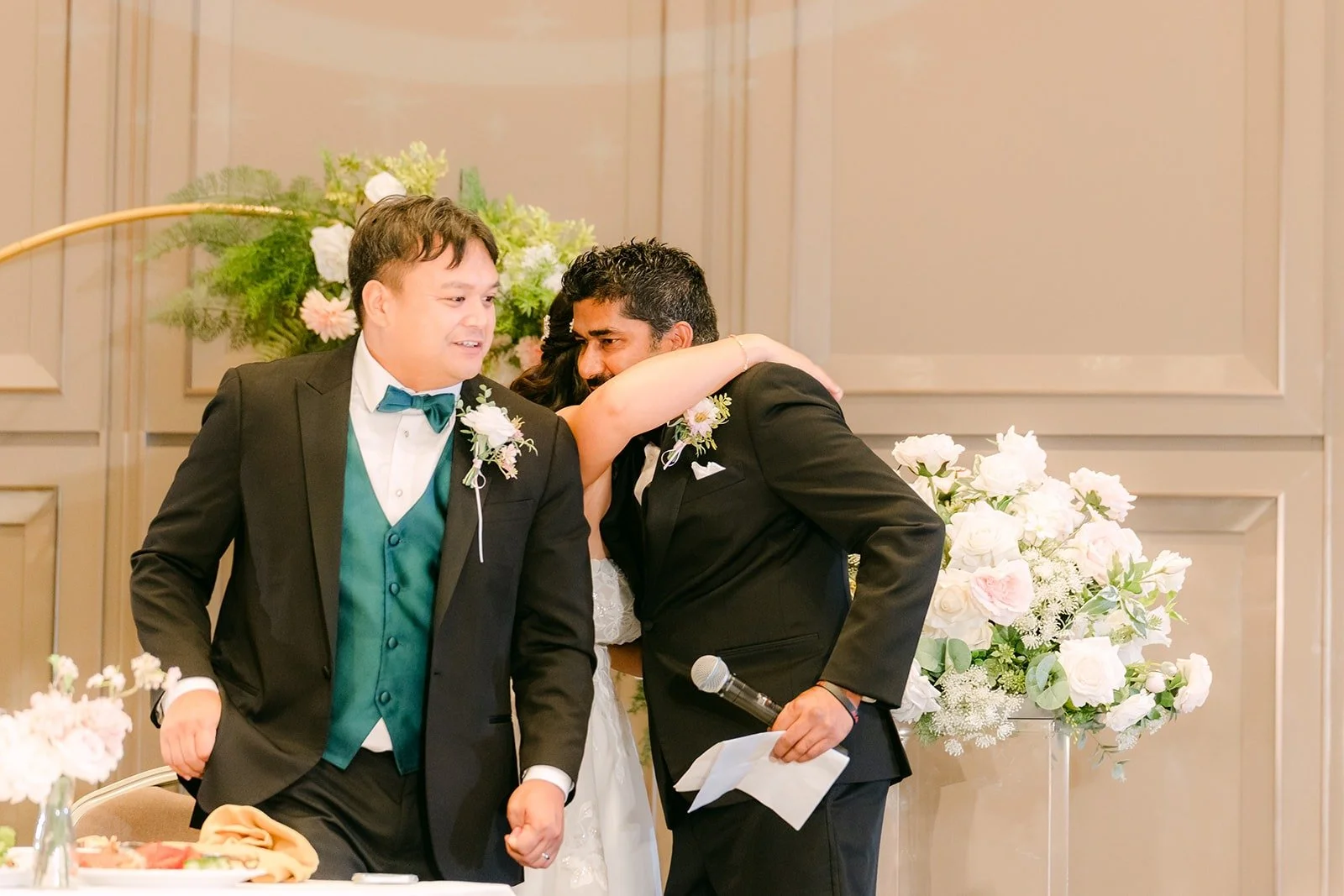 James laughing with a groomsman at the sweetheart table during the speeches