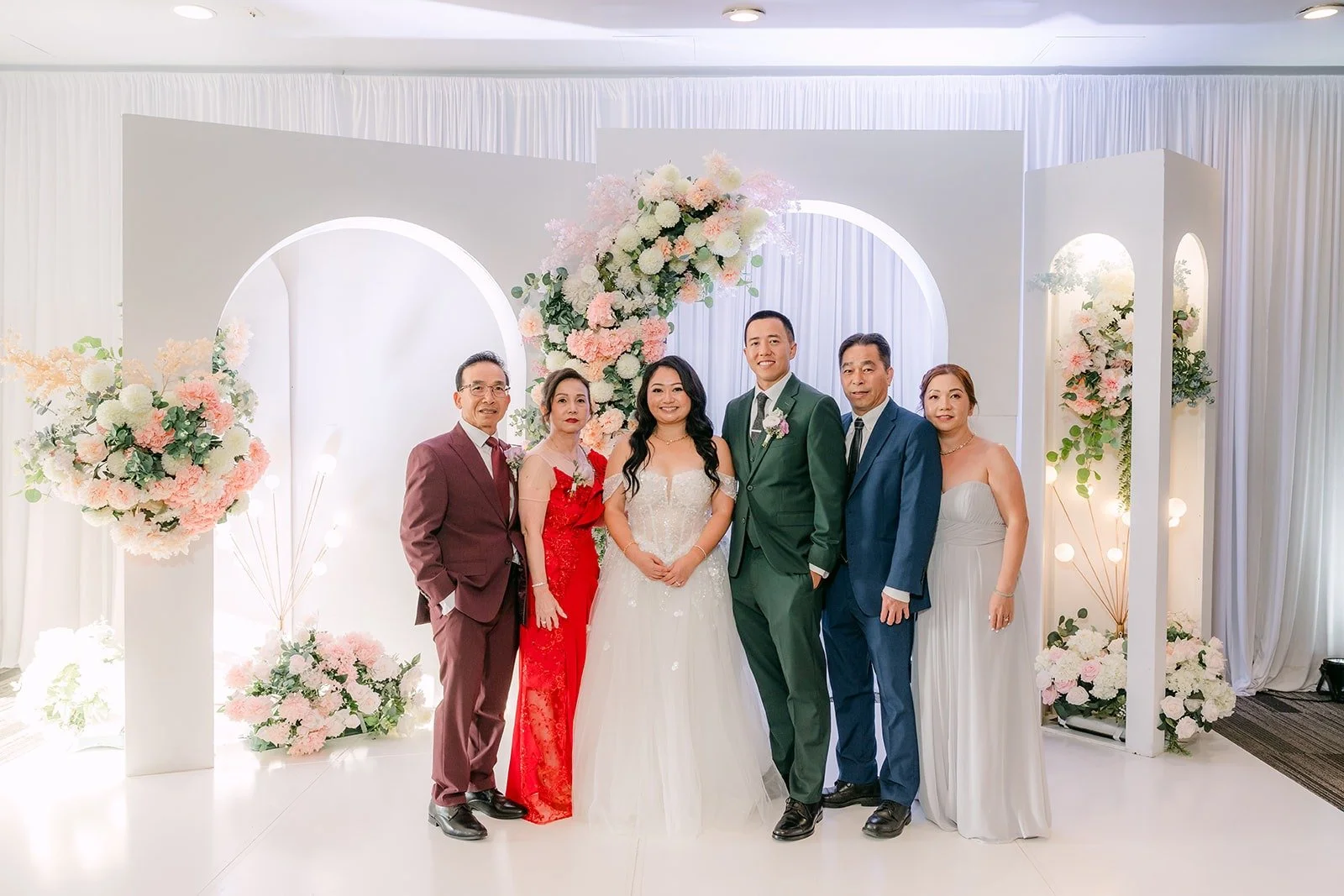 Jennifer and Kevin welcome guests for photos at the white arch backdrop