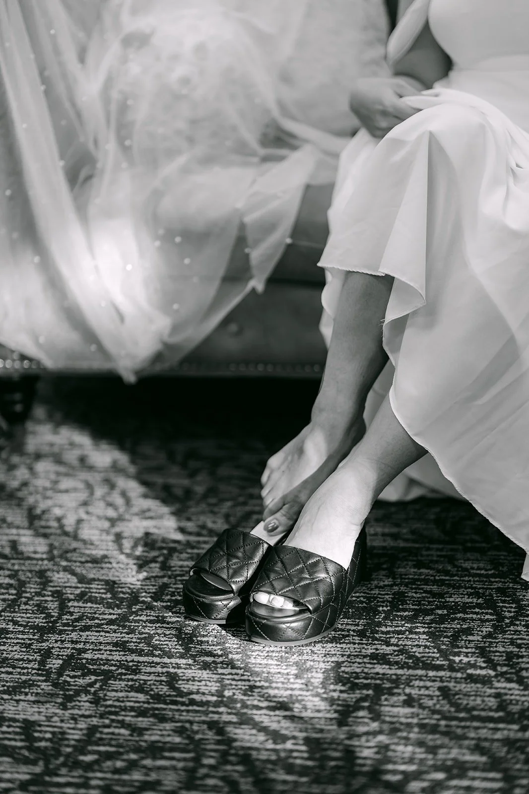 Black and white of Ivy slipping on her wedding shoes