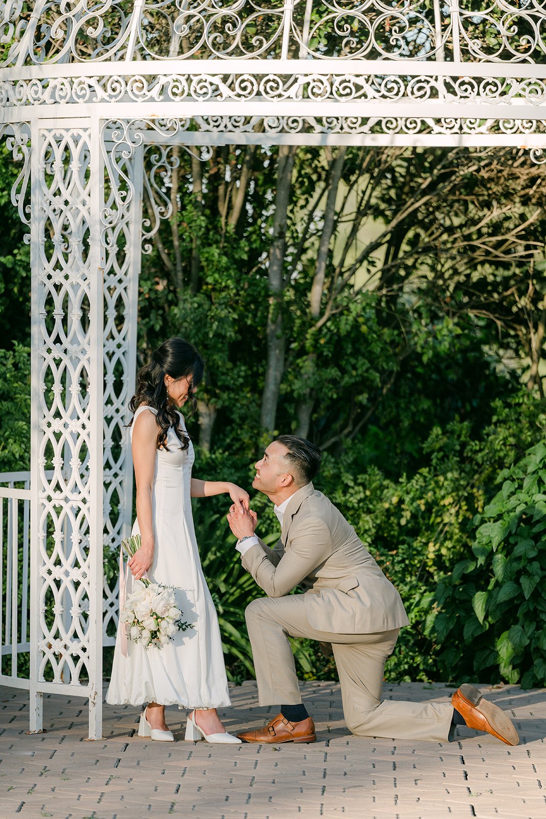 Vincent kneels before Kim inside the white gazebo.