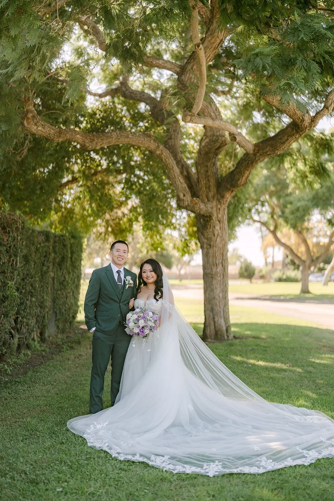 Jennifer and Kevin under a wide tree at Garden Grove Park with her train spread on the lawn