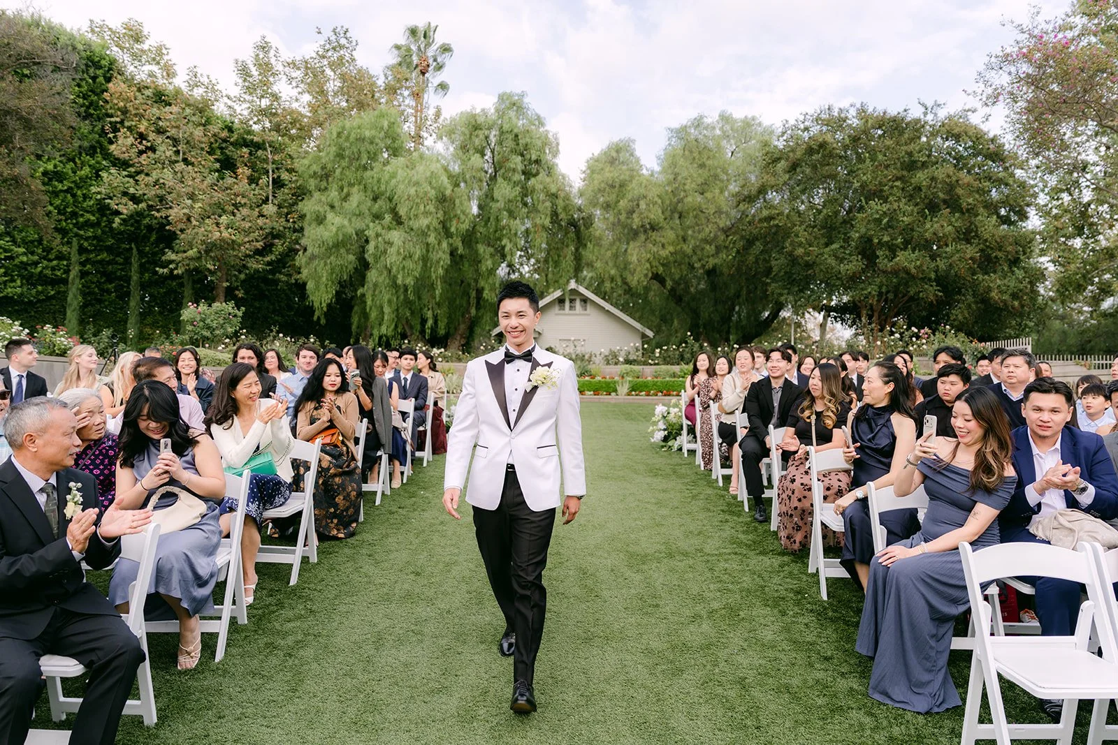 Ryan walking down the aisle on the lawn as guests watch.