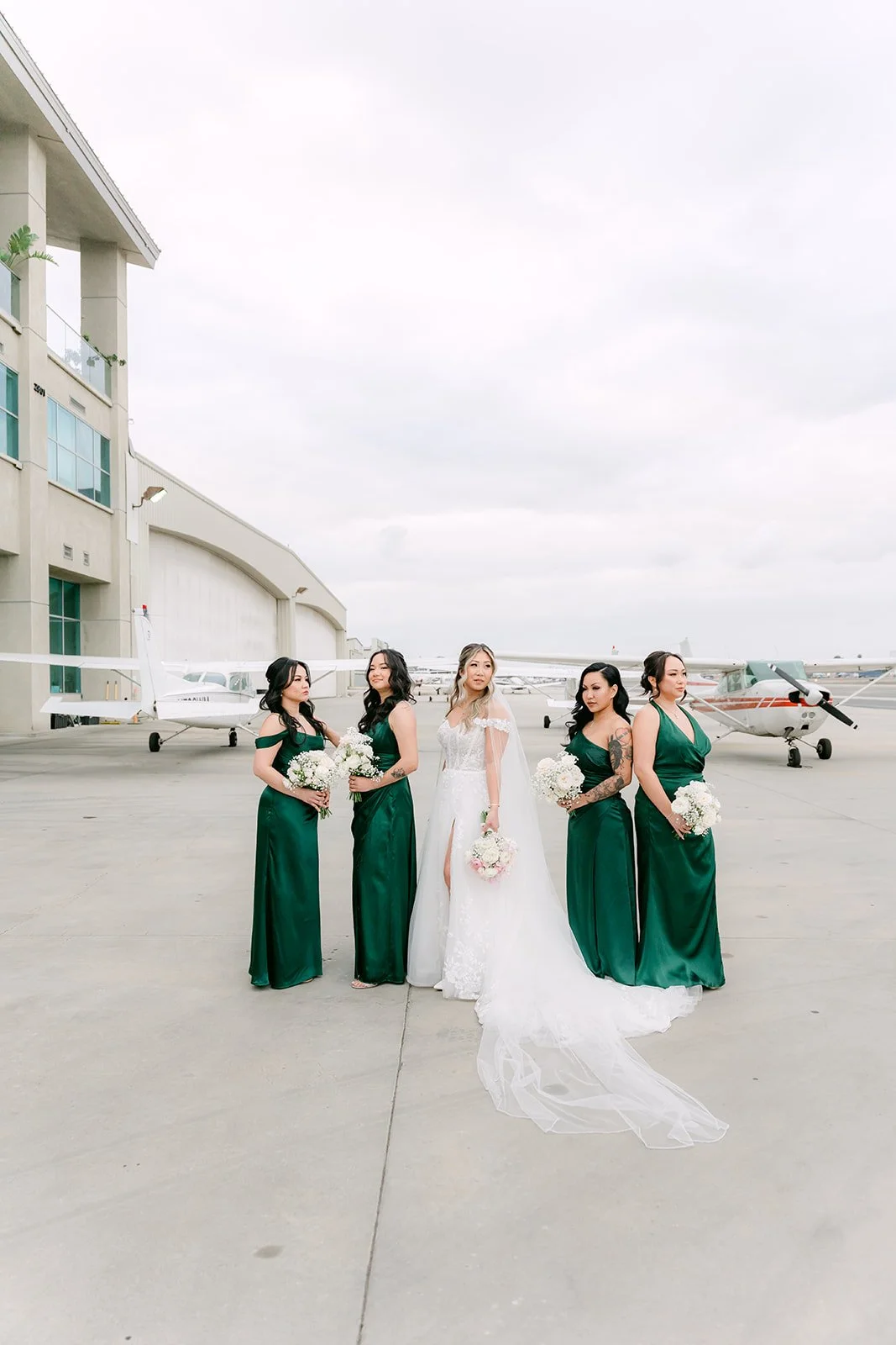 Bride with bridesmaids in emerald satin walking on the tarmac