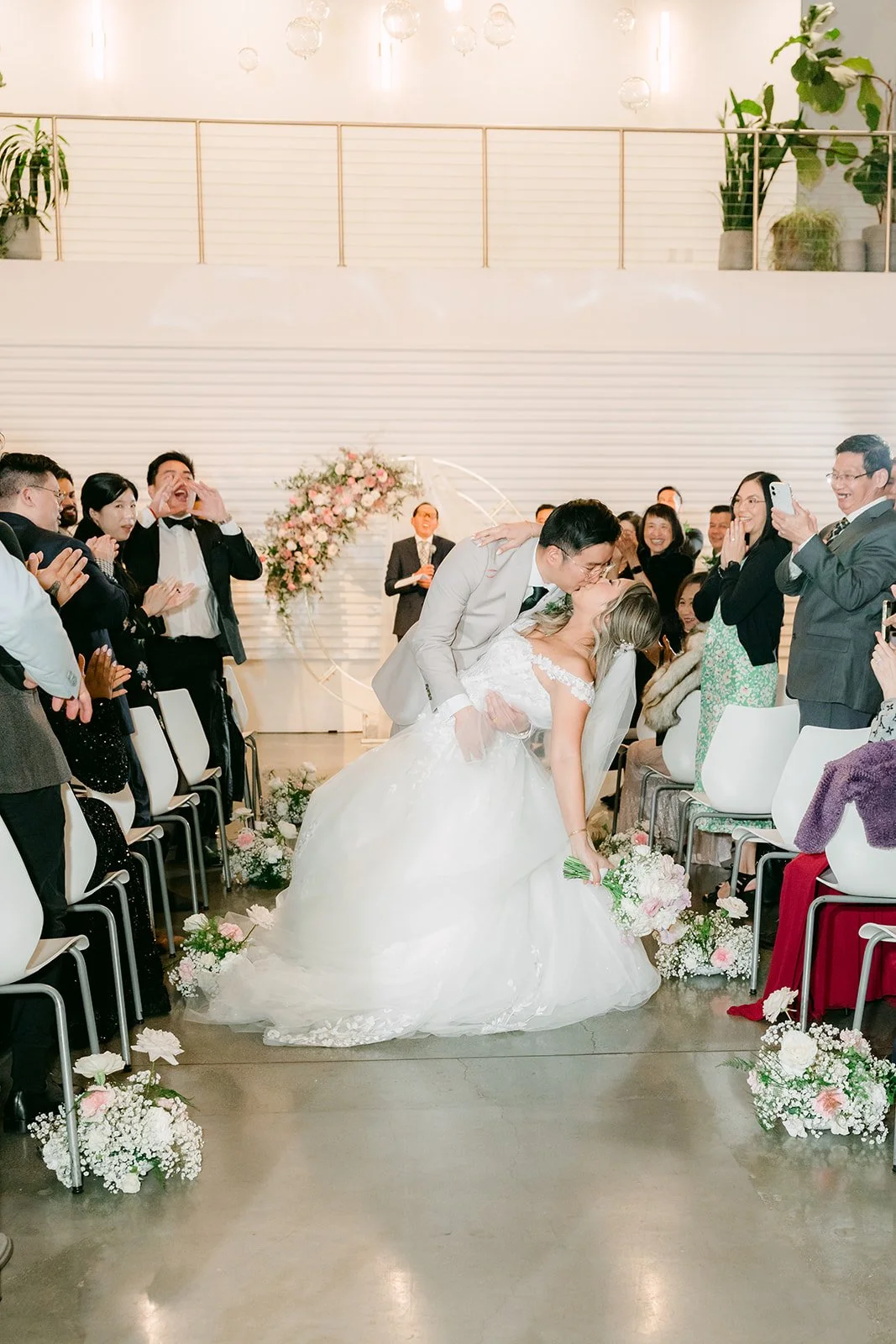 Raine and Ricky kissing in the aisle as guests cheer
