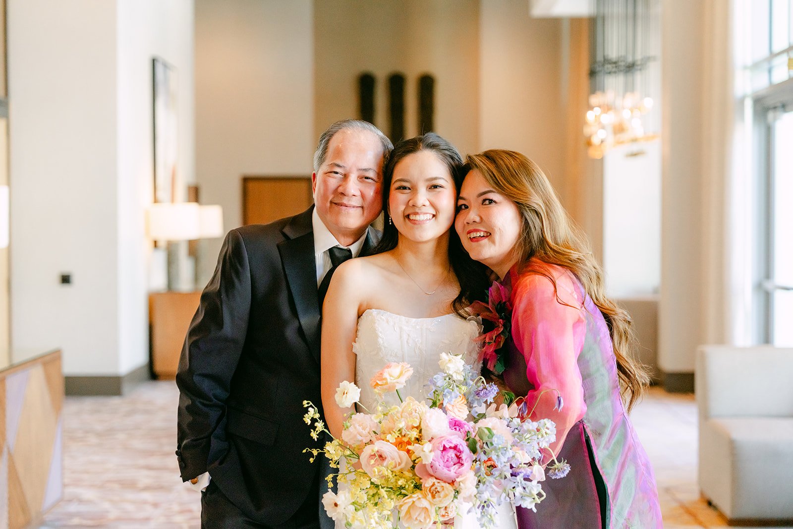Bride hugging her parents in the hotel lobby