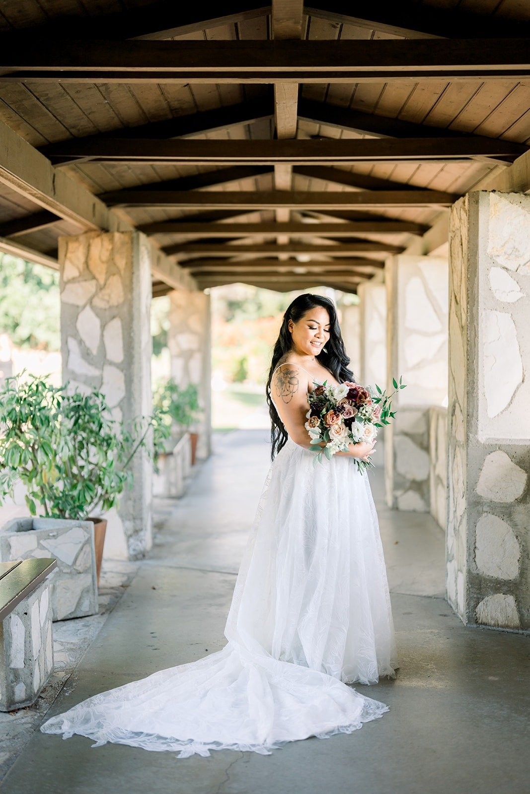 Betsy with her bouquet in a wooden covered walkway with stone pillars