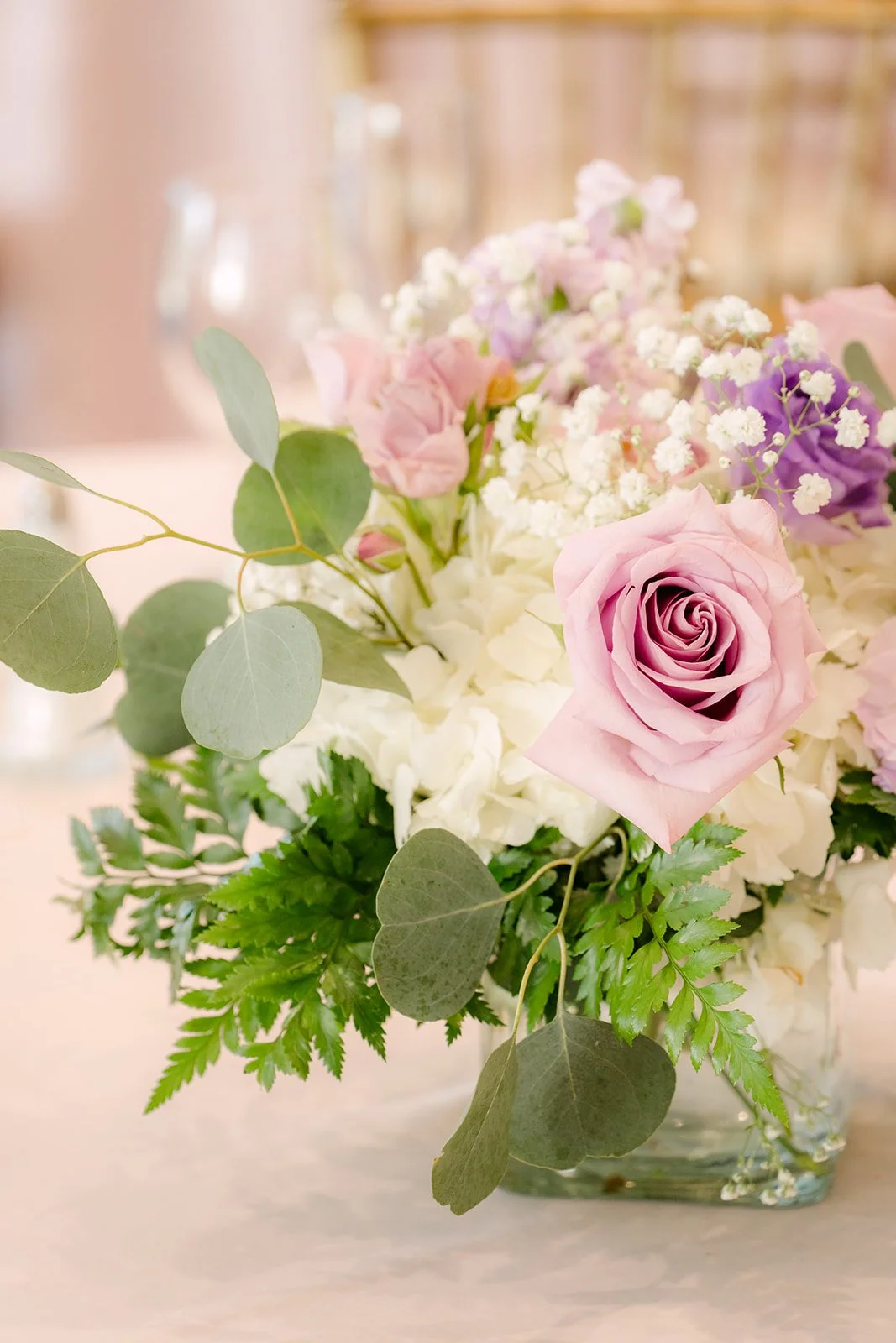 A centerpiece of lilac roses and white blooms.