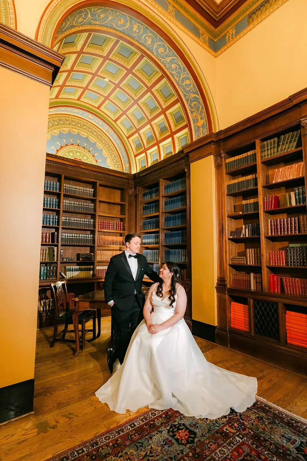Saira and Matthew under the painted vaulted ceiling of the Athenaeum library