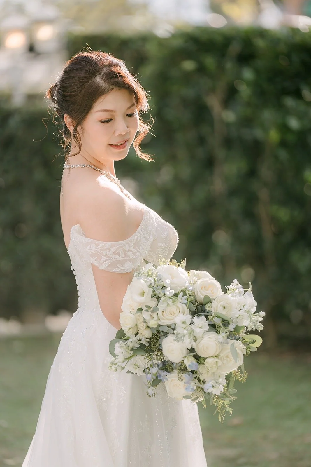 Portrait of Sochi with her bouquet against the hedge, photographed by One and Only Production