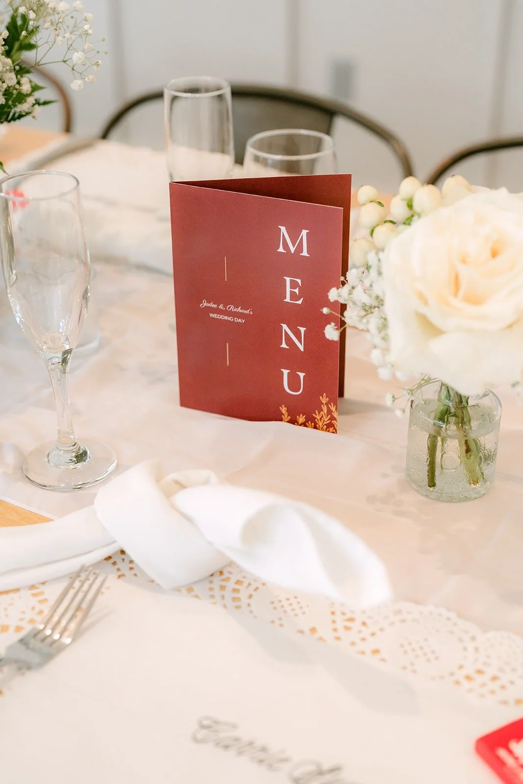 A burgundy menu card at a place setting with white flowers
