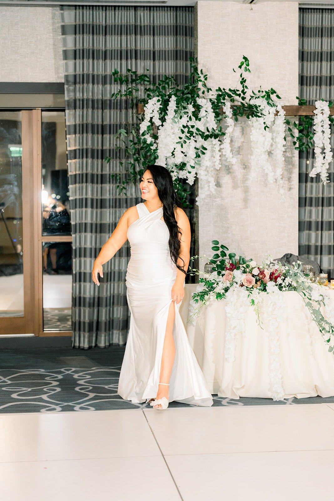 Betsy in her white satin second look by the sweetheart table