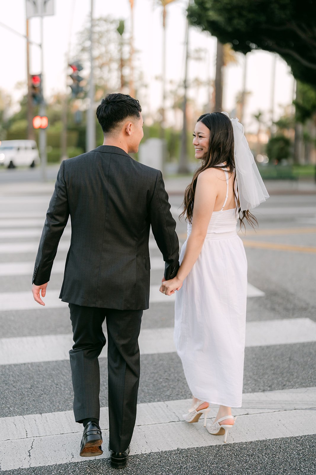 Jadee and Richard cross the street together, her veil trailing behind her.