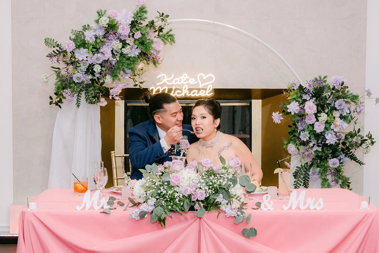 Kate and Michael at the sweetheart table with lilac florals.