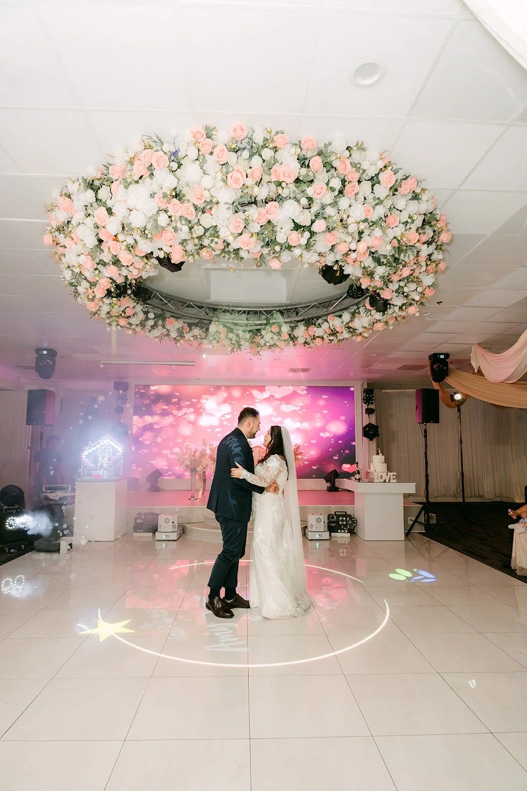 Wide view of the first dance under the floral chandelier