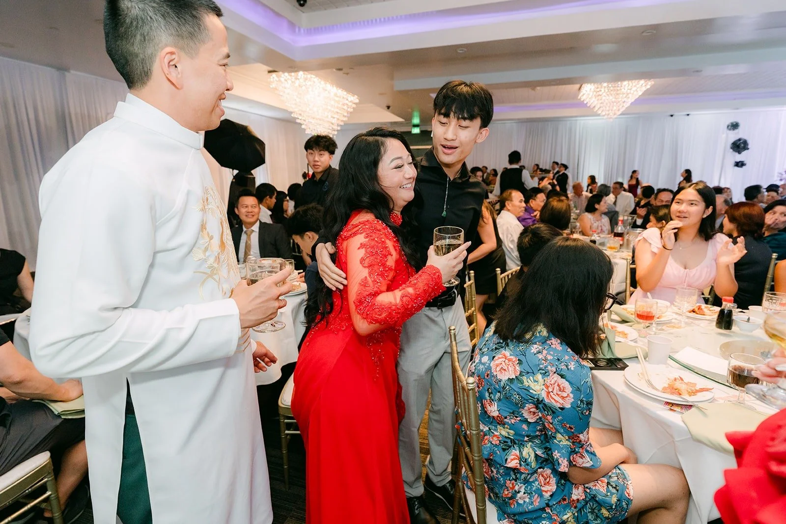 Kevin in his white ao dai raises a glass at a guest table