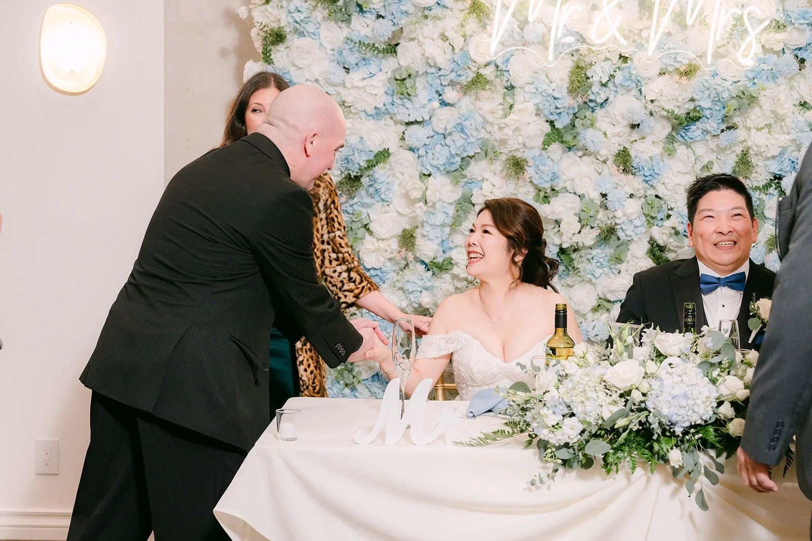 A guest greets Sochi and Jay at the sweetheart table, photographed by One and Only Production
