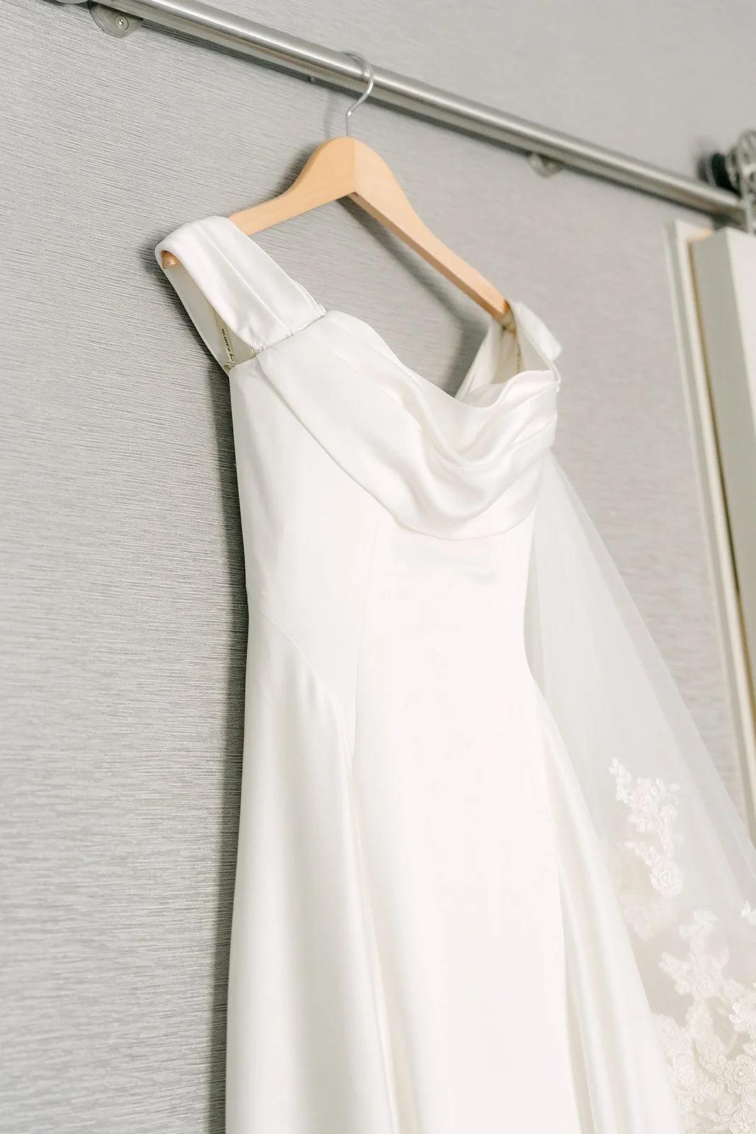 Amanda's off-the-shoulder wedding gown hanging by the window.