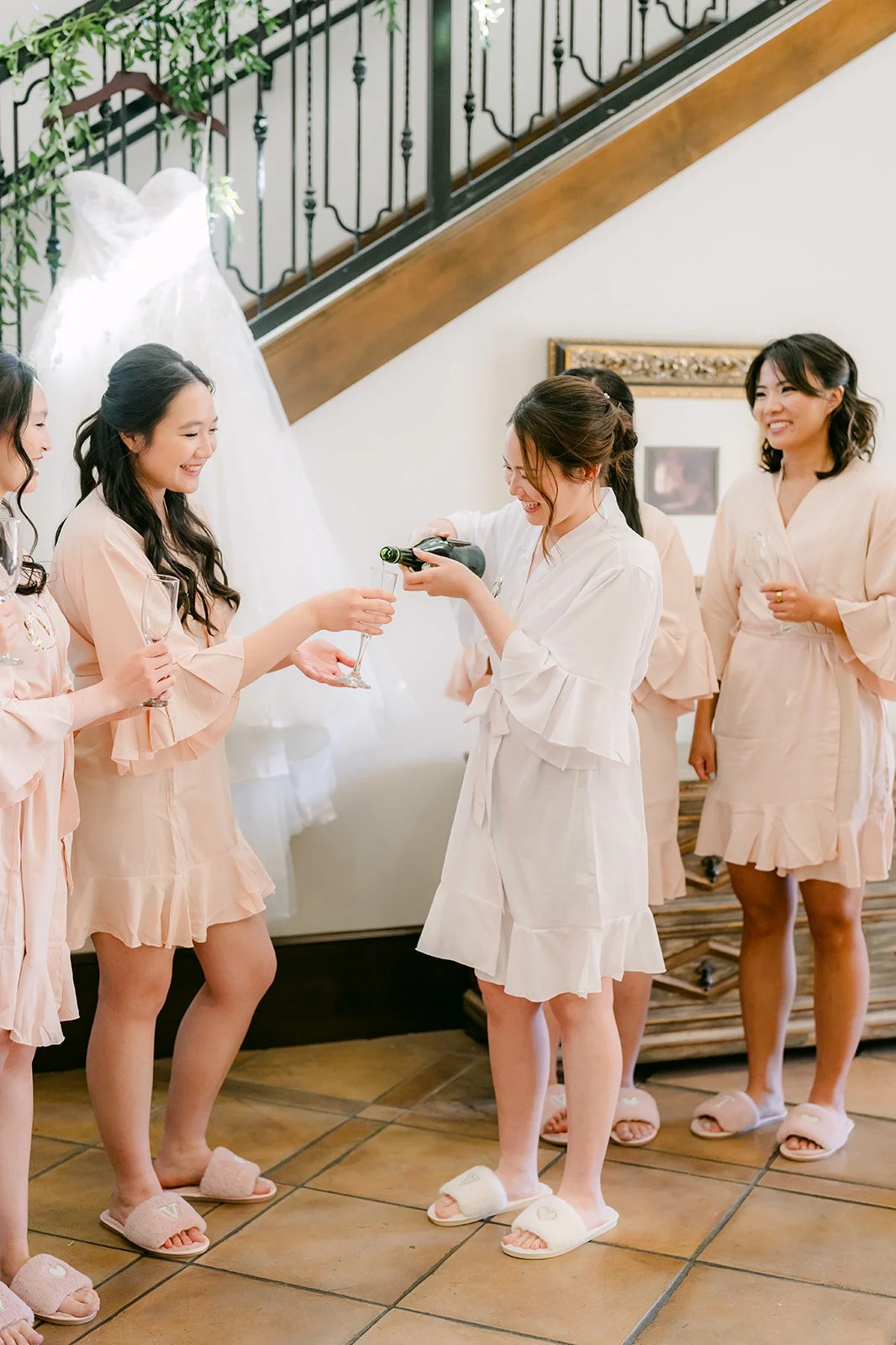 Bride pouring champagne for her bridesmaids during getting ready