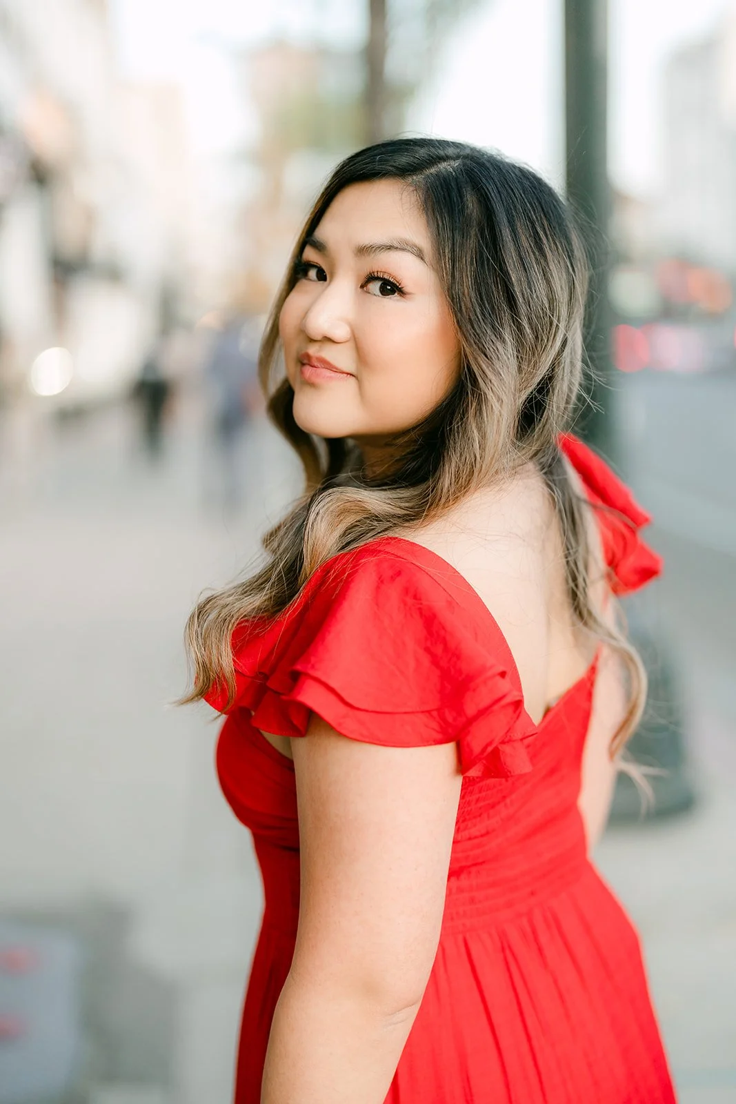 Linh smiles over her shoulder on the sidewalk.