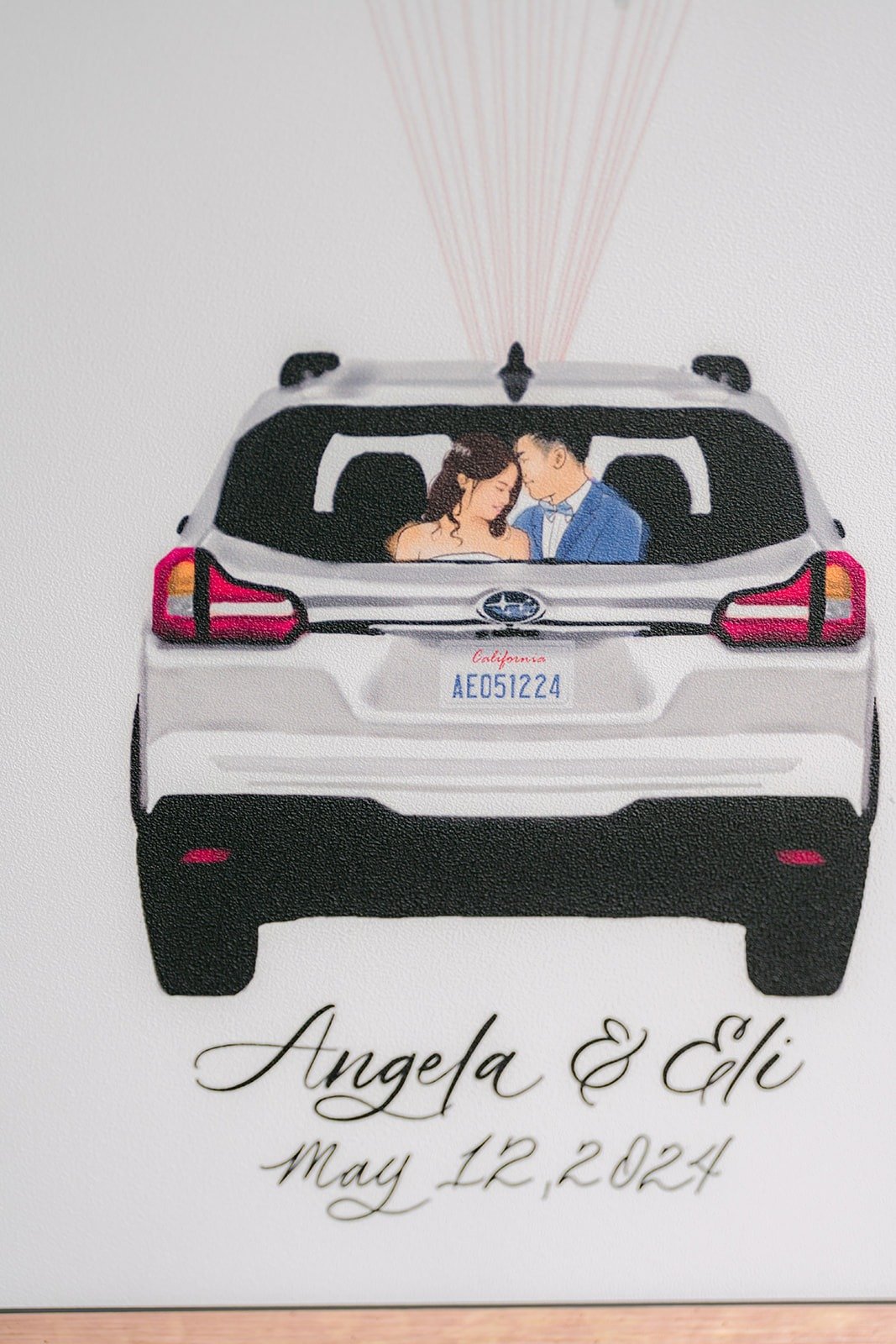 A hand drawn sign of Angela and Eli in their car, dated May 12, 2024