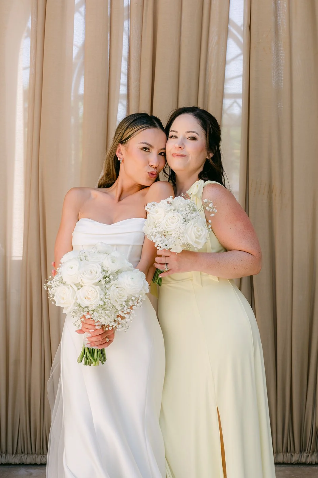Bride laughing with a bridesmaid in butter yellow, photographed by One and Only Production