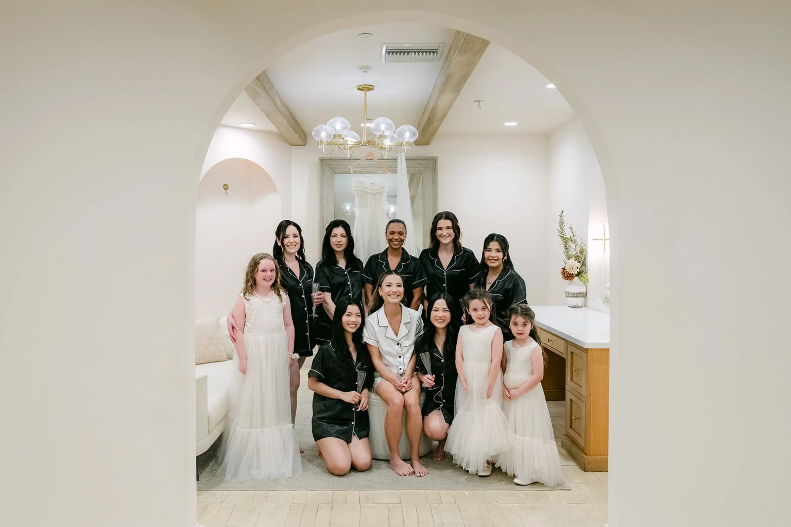 Bride and bridesmaids in black robes framed by the arched doorway of the bridal suite