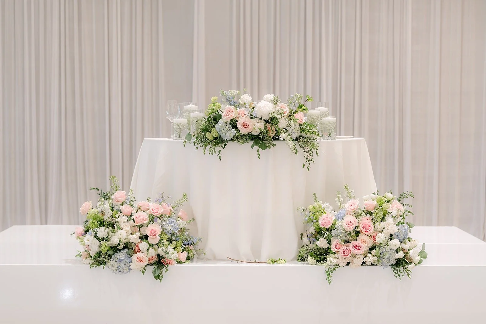 The sweetheart table with white draping and blush and white arrangements