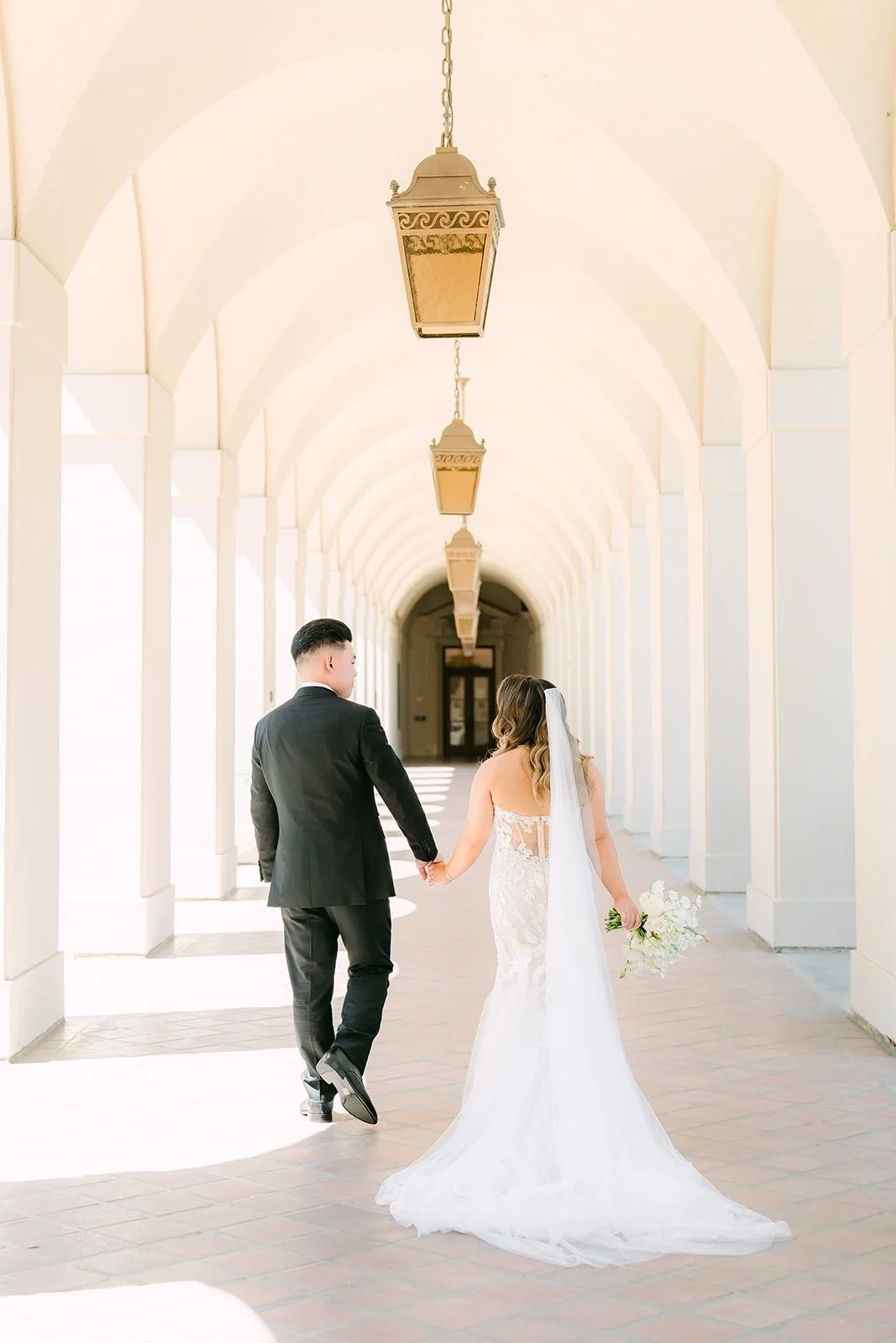 Candice and Vincent walking down the arched colonnade at Pasadena City Hall