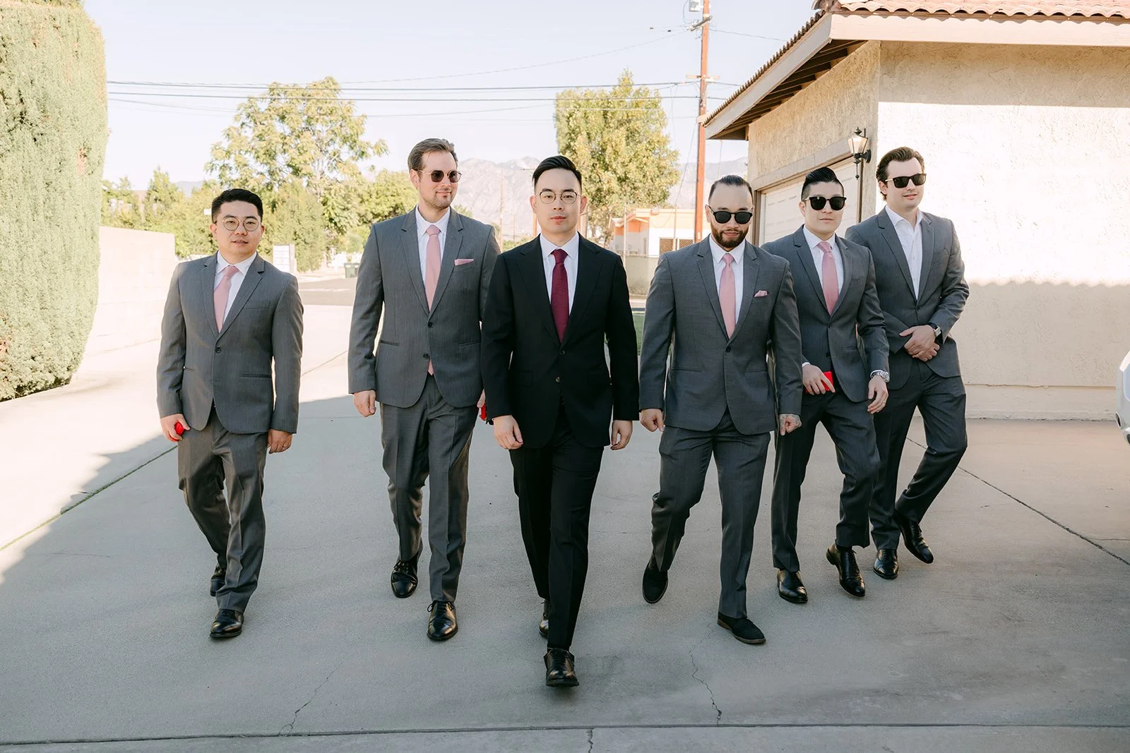 Ken and his groomsmen in grey suits walking up the driveway.