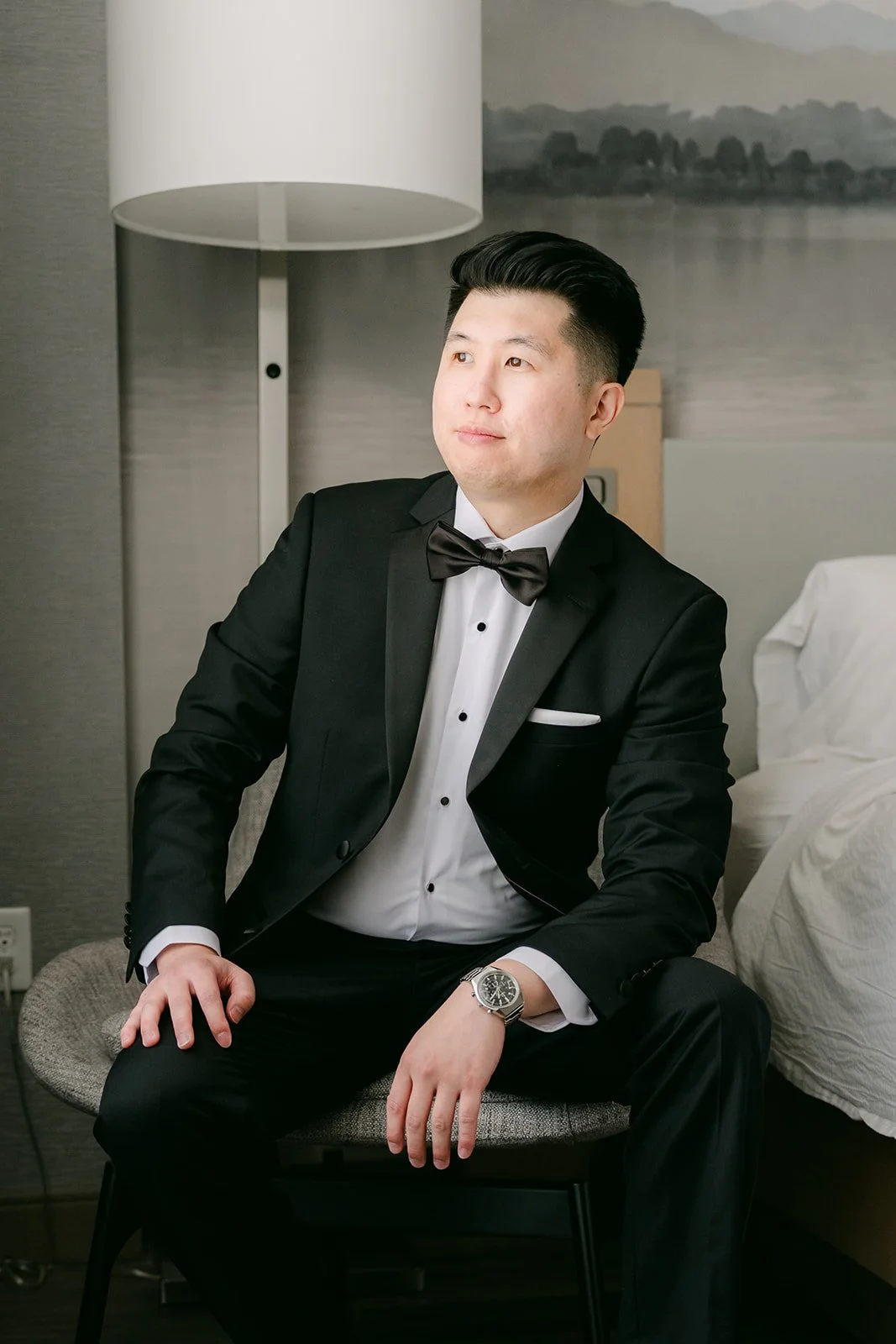 San sitting in his black tuxedo in the hotel room.
