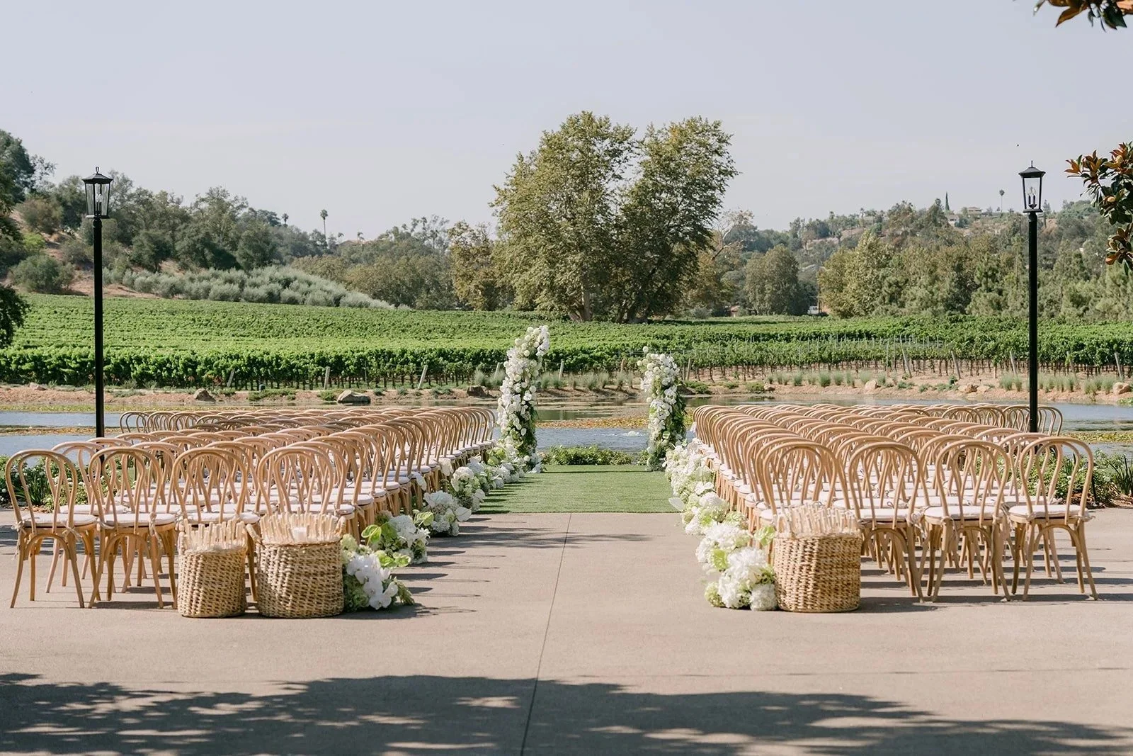 Monte Bella pond ceremony with rattan chairs and a white floral aisle at Monserate Winery