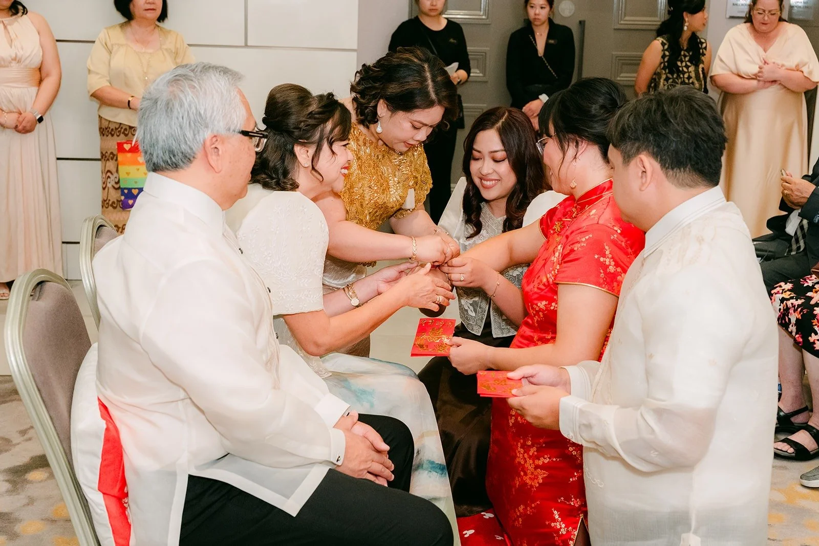 Family members passing red envelopes to Stella and James after receiving tea