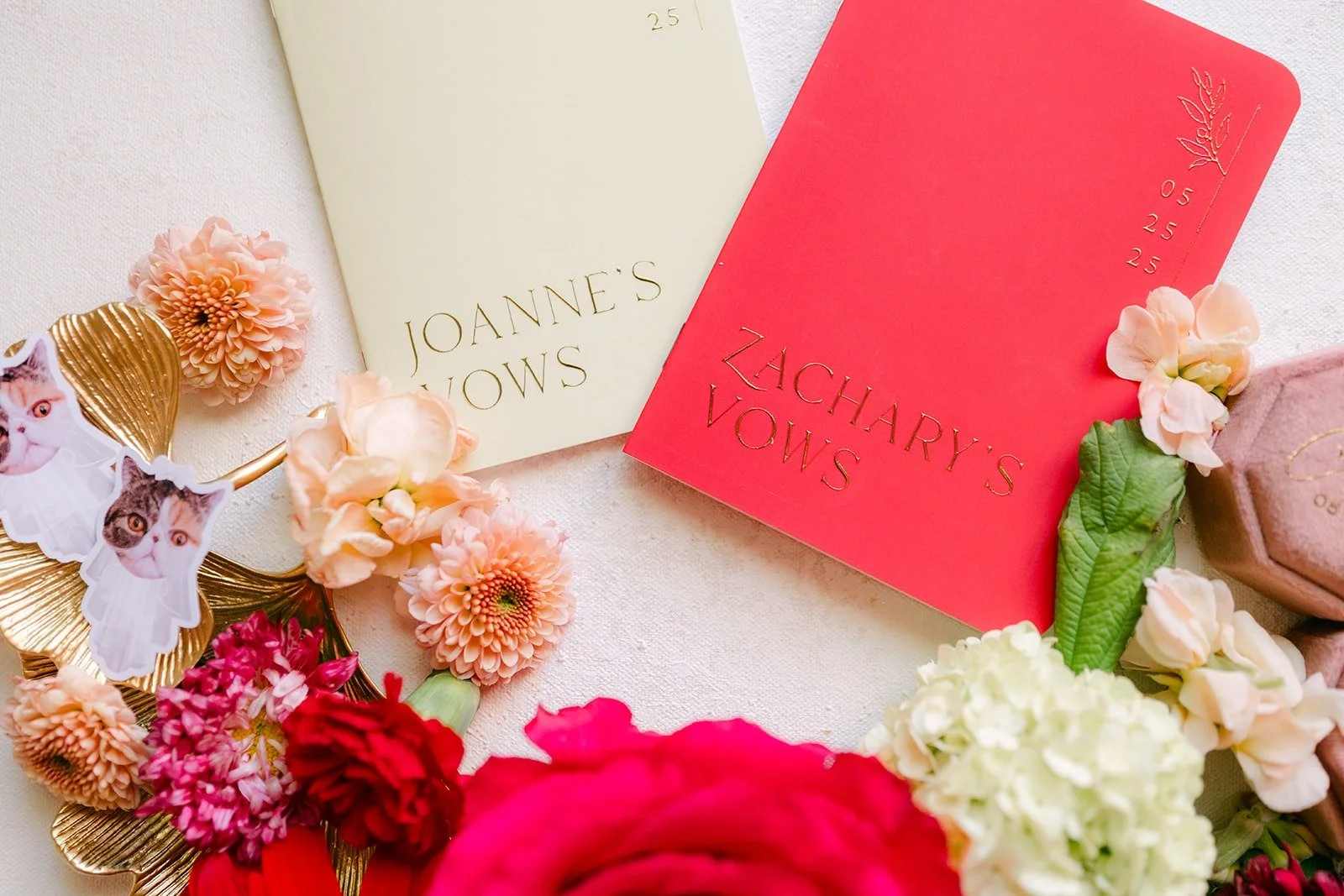 Red and cream vow books laid out with pink and red flowers
