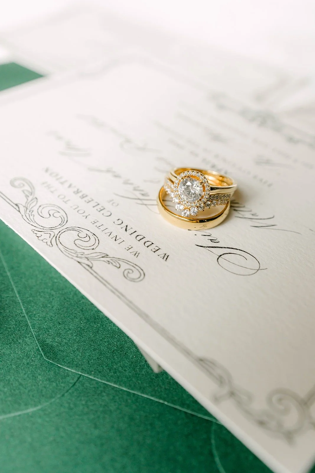 Their wedding rings resting on the invitation and a dark green envelope
