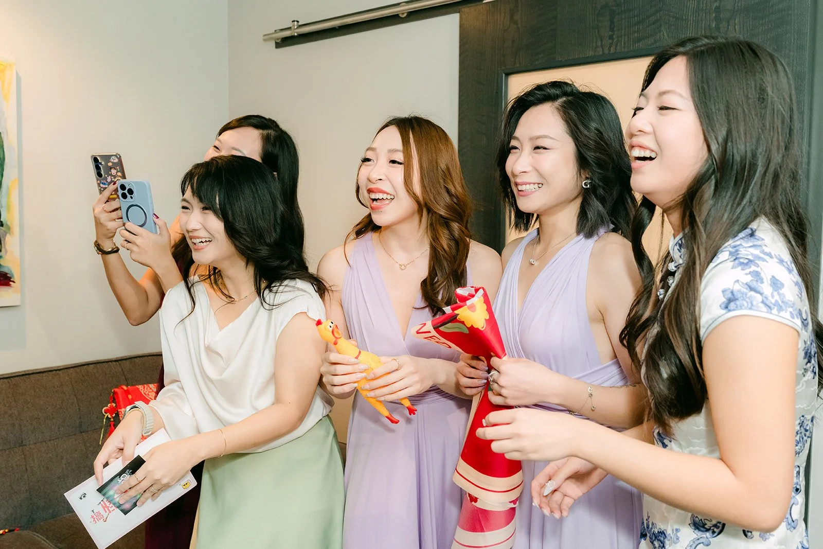 Bridesmaids holding up signs and red envelopes behind the door.