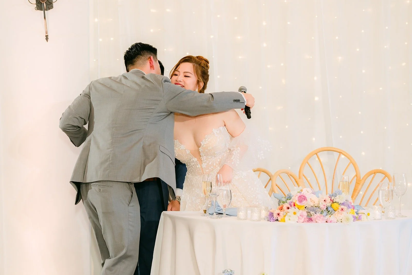 A groomsman hugging Joanna and Jerrick after his speech