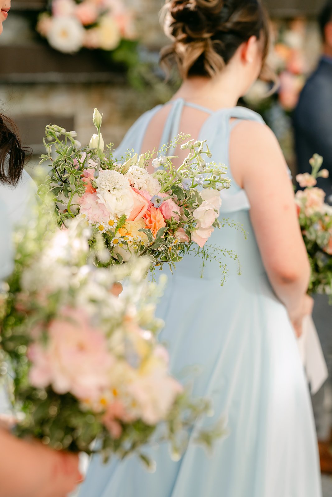A bridesmaid in light blue holding her bouquet during the ceremony.