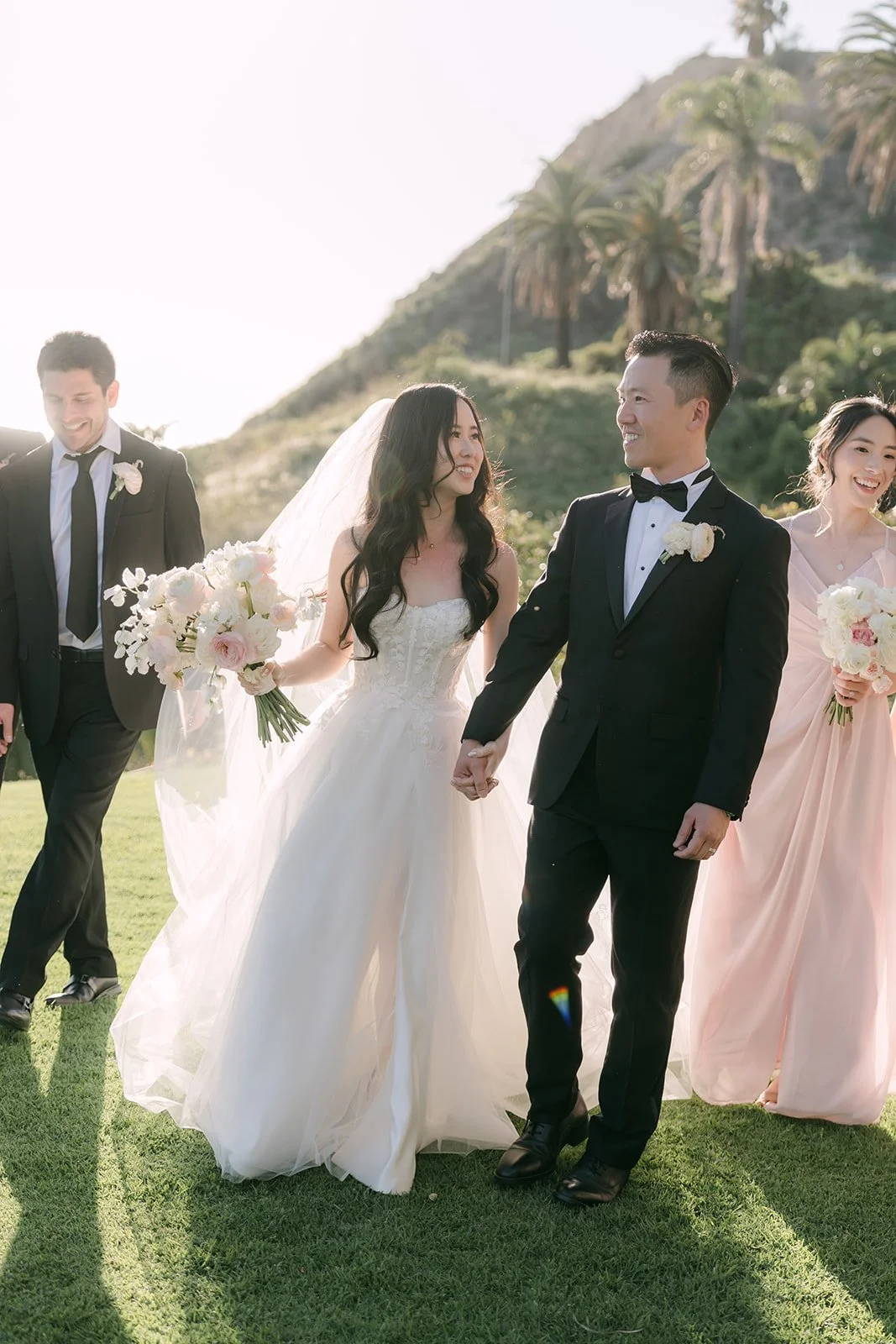 Couple laughing with their wedding party on the lawn