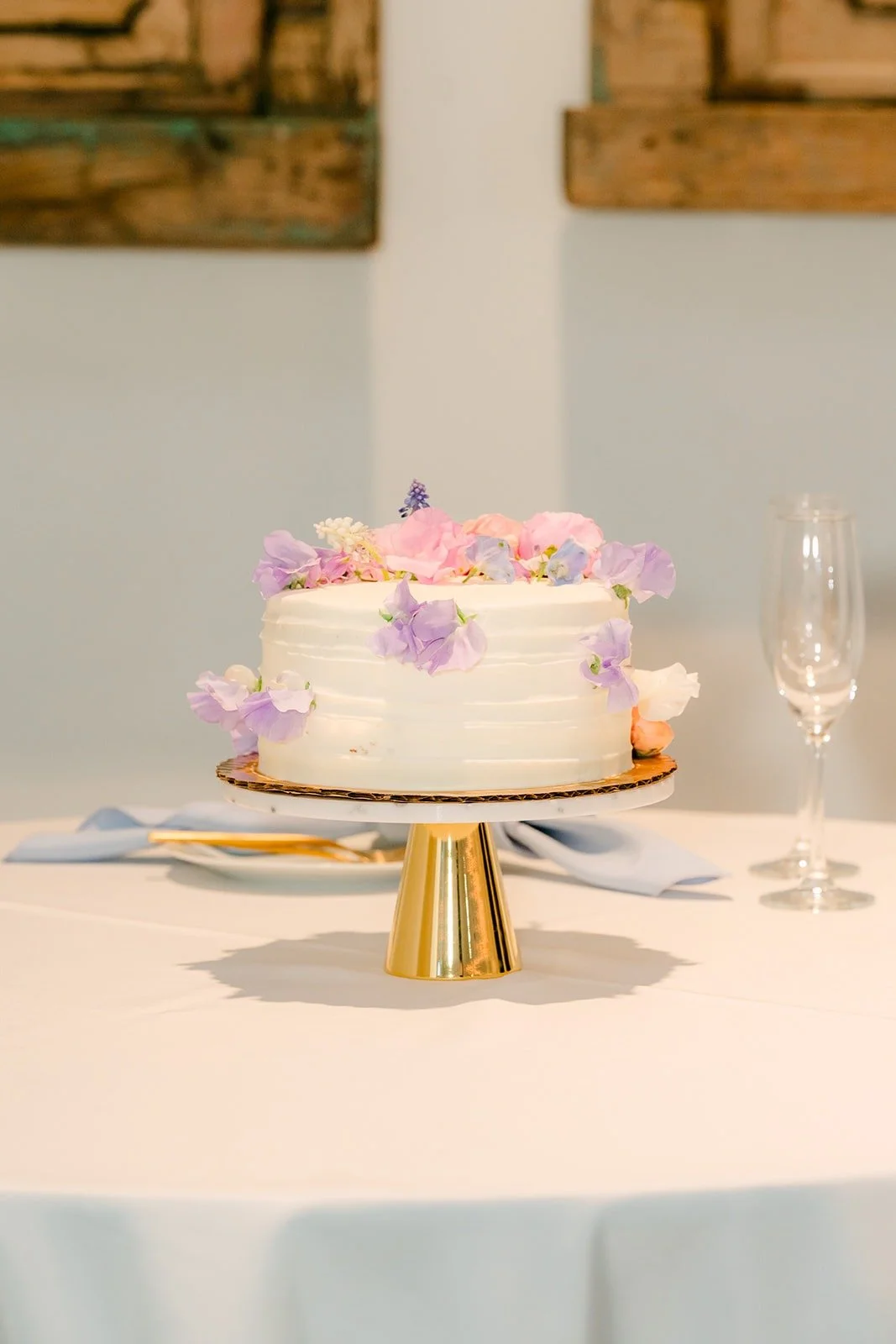 The cake with lavender and pastel flowers on a gold stand