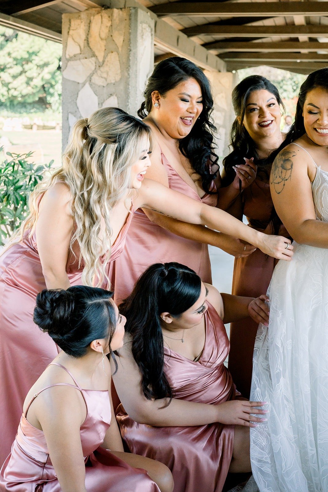 Bridesmaids fluff Betsy's train and adjust her gown