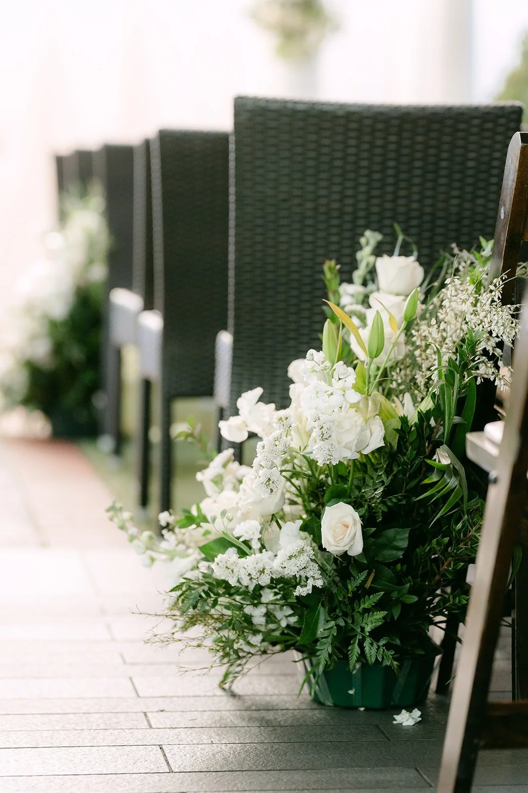 White flowers lining the aisle beside black ceremony chairs